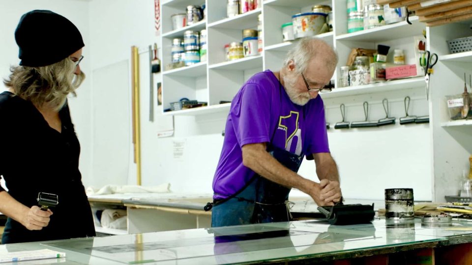 Le technicien Paul montre à Catherine des techniques de gravure.
